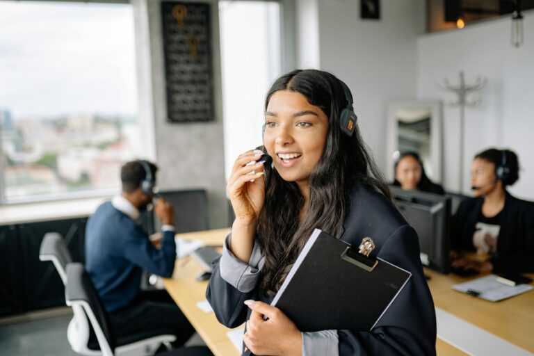 A smiling call center agent with headphones works in a modern office.